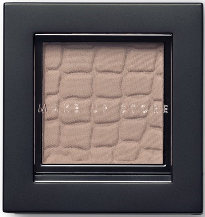 En makeup-compact med beige puder, med en diamantmönstrad textur och orden "MAKE UP STORE" på.