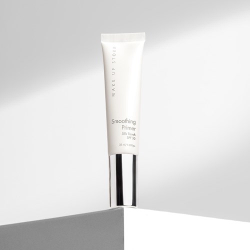 A white tube with silver cap stands on a corner, label shows it is a smoothing primer with SPF 30.