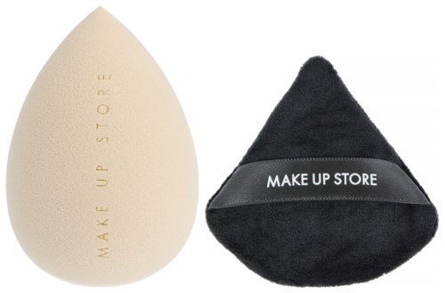 A makeup sponge and a cleansing sponge from Make Up Store. The makeup sponge is teardrop-shaped, the other is black and triangular.