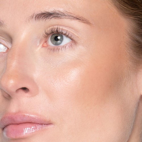 Nahaufnahme eines Frauengesichts mit klarer Haut, blauem Auge und natürlichen Zügen mit minimalem Make-up.