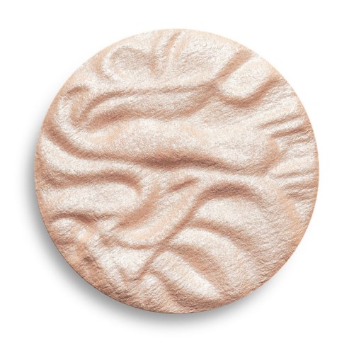 Een ronde, beige make-upproduct met textuur en golvende oppervlak en een lichte schaduw eronder.