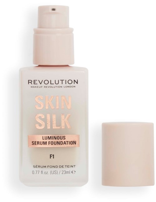 Een witte fles met pump en afneembaar deksel, gelabeld "Revolution Skin Silk Luminous Serum Foundation," met roze en zwarte tekst.
