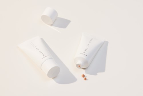 Twee witte tubes, een geopend met pillen die eruit vallen, en een andere gesloten op een witte achtergrond.
