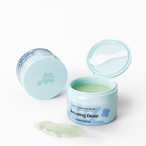 Ein kleiner Behälter mit Minzreinigungsbalsam, Deckel offen, Balm und verschüttet auf Oberfläche.