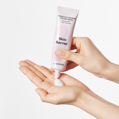 Een hand knijpt witte crème uit een tube met label 'Skin Barrier' op in de handpalm.