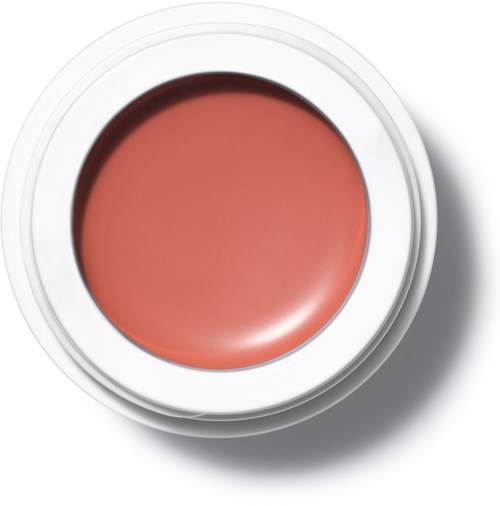 Ljus orange kräm i en vit behållare med skugga, inget annat text eller föremål syns.