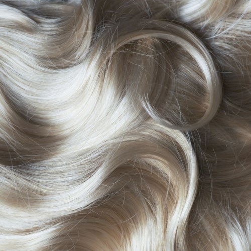 Blonde hair with shiny, loose curls and a white hair tie or band.