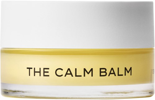 Ett burk med vit lock och gul kropp, märkt "THE CALM BALM."