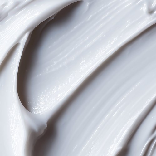 Nahaufnahme einer glatten, weißen, cremigen Textur, möglicherweise eines Kosmetik- oder Lebensmittelprodukts. Wirbelmuster sichtbar.