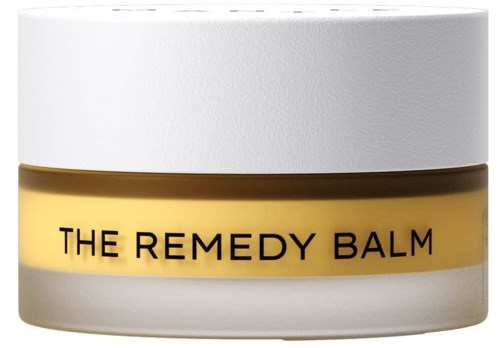 Kleine runde Dose mit weißem Deckel und beigem Körper, beschriftet 'THE REMEDY BALM'.