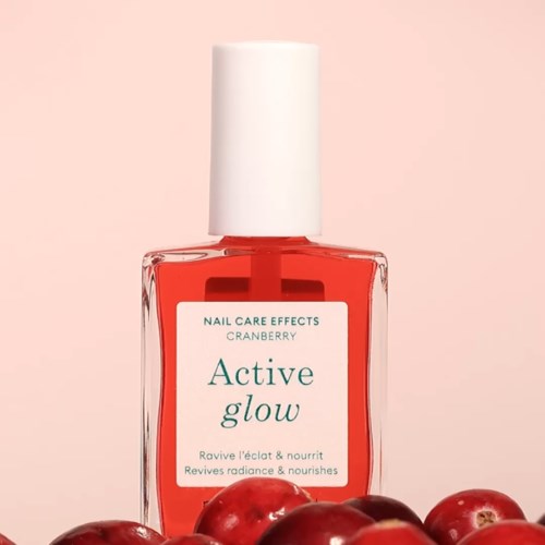 A nail polish bottle with cranberry color and a white label, surrounded by fresh cranberries.