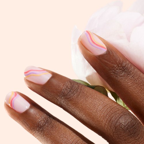 Nail art with colorful wavy lines on light pink nails held with a white flower.