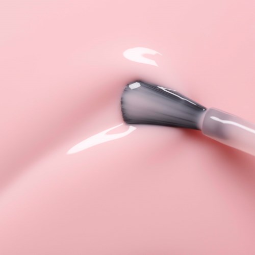 A makeup brush applying foundation on smooth, pink skin.