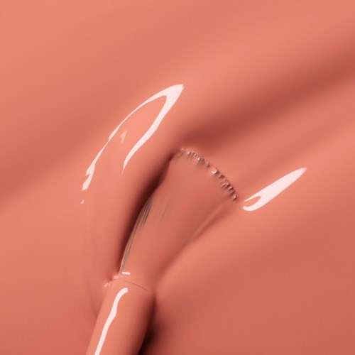 A close-up of a shiny, metallic object against a soft, pinkish background.
