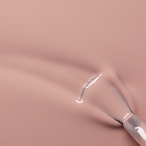 A makeup brush is applying foundation or concealer on smooth skin.