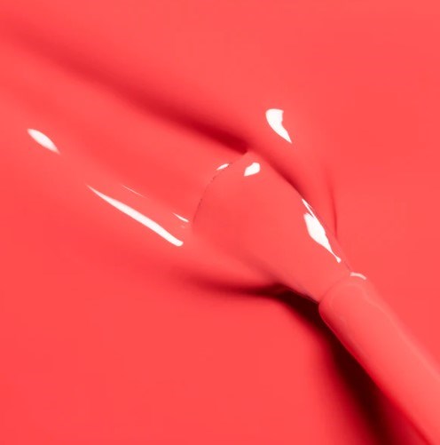 A pink lipstick with some gloss lies on a matching pink background.