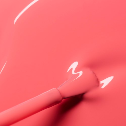 A pink lipstick is applied to a pink surface, creating a smudge and a slight smearing effect.