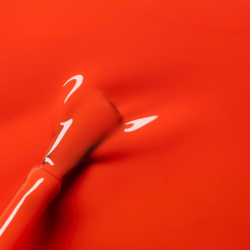 A red fabric with a shiny, flowing motion and a white curving line or shape on it.