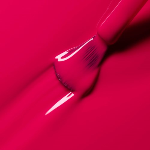 Close-up of a makeup brush applying pink lipstick on lips.