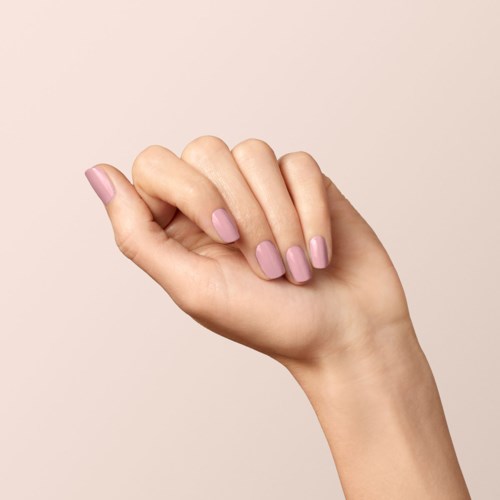 En hand med ljuslila nagellack är i en mjuk knytnäve mot en ljus bakgrund.