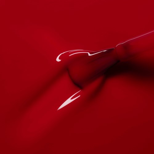 A red lipstick with a white streak on the surface, showing a close-up of the lipstick's tip against a red background.