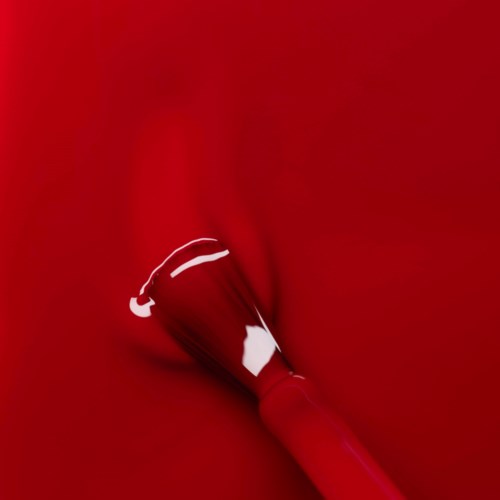 A red lipstick lying on a red fabric background.