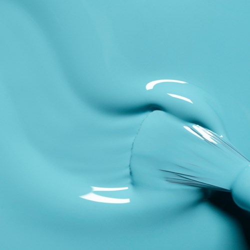 A person wearing gloves is applying a smooth, shiny blue surface, possibly paint or a similar material.
