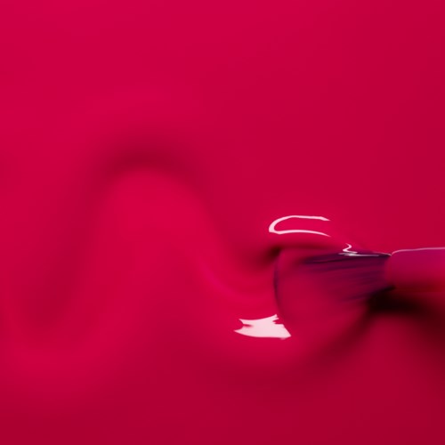 A close-up of a shiny pink lipstick tube with the cap off.