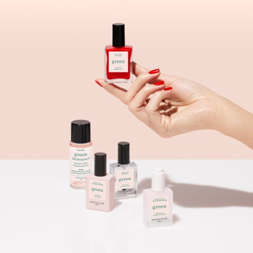 Five bottles of nail polish and remover placed on a white surface, with a hand holding a red bottle.
