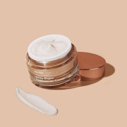 Een potje crème met een lepel crème en een gesloten deksel op een roze achtergrond.