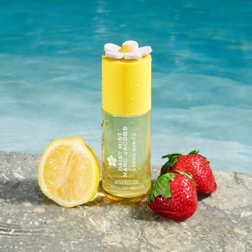 A yellow and green spray bottle with lemon and strawberry beside a lemon half on a stone surface.