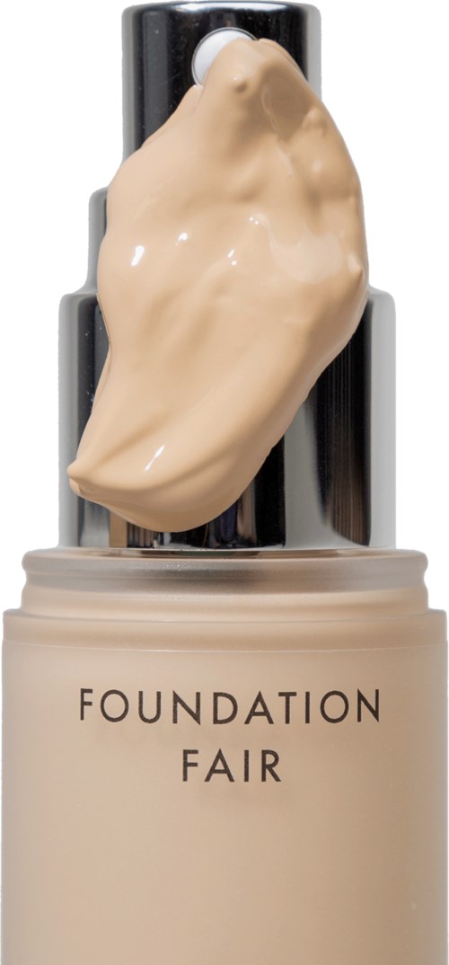 Eine Flasche mit den Worten 'FOUNDATION FAIR' und einer beige Creme oder Grundierung auf einem schwarzen Applikator.