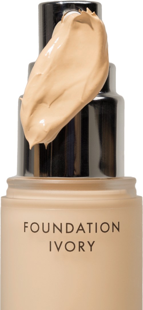 Een flesje ivorykleurige foundation met een dollop van dezelfde foundation erop. De fles heeft een zwarte dop.