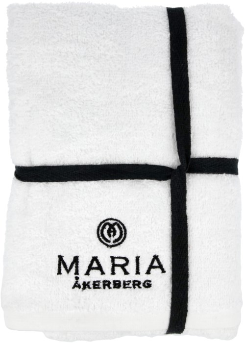 A soft white towel with black ribbon and a logo with the name Maria Akerberg.