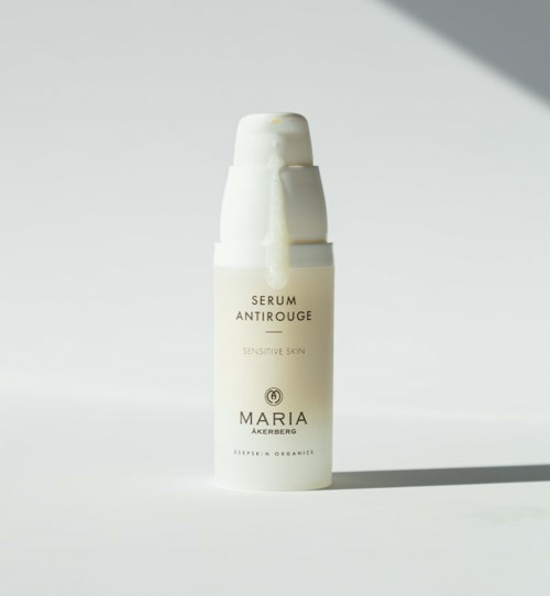 A white bottle labeled 'Serum Anti-Redness' for sensitive skin with a pump top on a plain background.