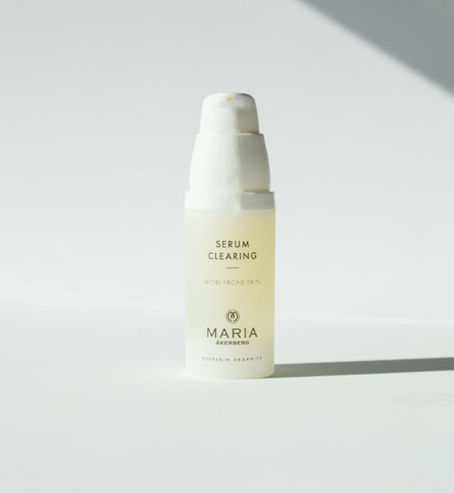 Een witte fles met de tekst 'Serum Clearing' en 'Maria Akerberg' staat op een eenvoudige achtergrond.