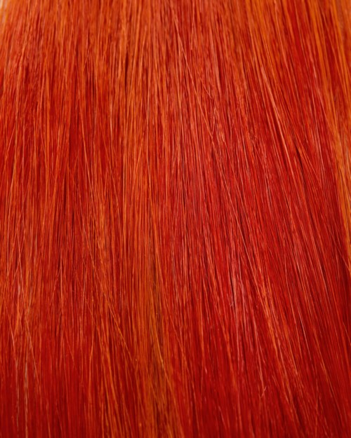 Close-up van levendige, rood-oranje haartextuur met fijne strengen.
