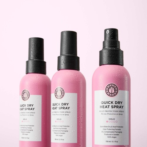 Three pink spray bottles labeled Quick Dry Heat Spray are shown with droplets, indicating moisture and freshness.