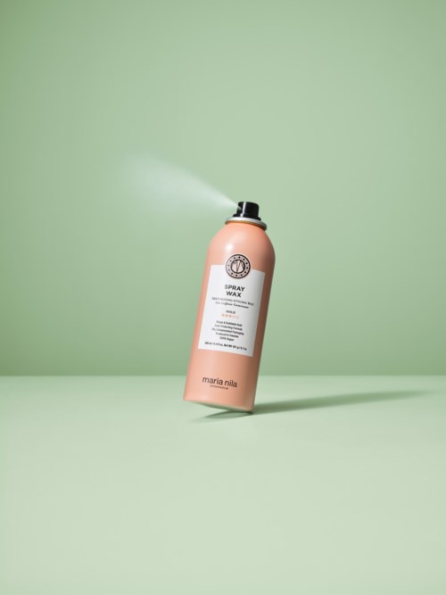 A pink spray bottle labeled 'Spray Wax' rises at an angle, spraying mist against a green background.