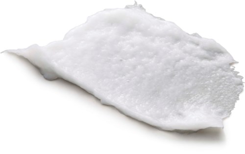 En vit, texturerad substans på ett svart papper, ser ut som en klump lim eller färg.