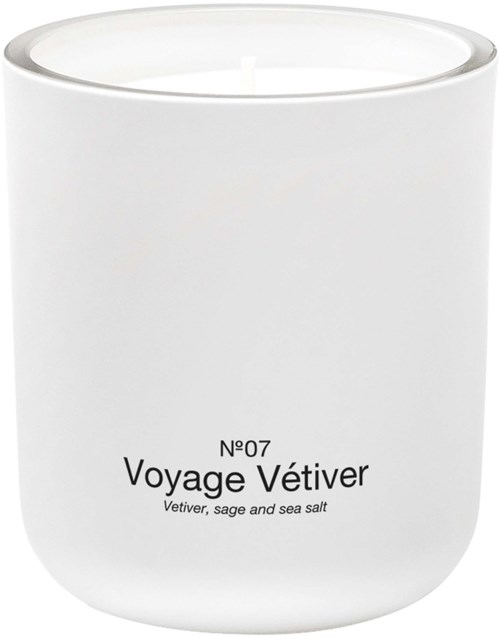 Ett vitt ljus i en enkel behållare med etiketten Voyage Vétiver. Den nämner salvia och havssalt.