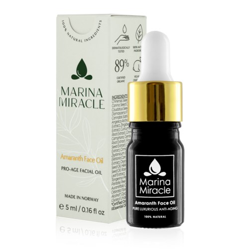 Kleine schwarze Flasche mit weißem und goldenem Deckel, beschriftet 'Marina Miracle Amaranth Face Oil', neben ihrer Verpackung.