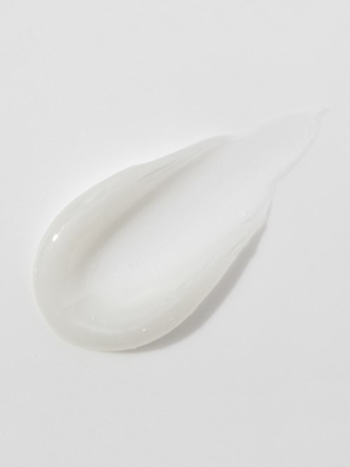 Een dot witte crème of lotion op een witte ondergrond, glad en glanzend.