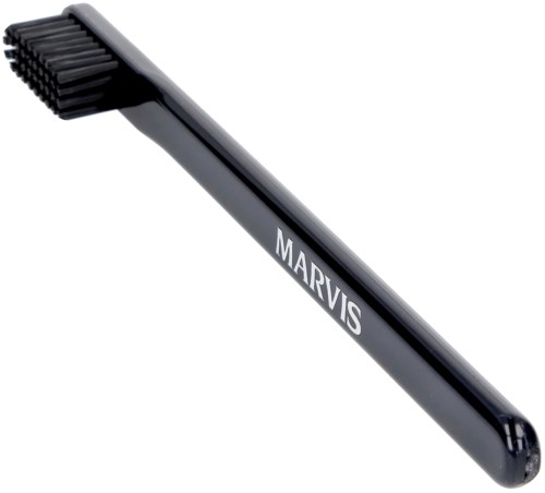 A black handled grooming brush with stiff bristles labeled "MARVIS."