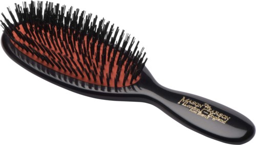 A black hairbrush with orange bristles and a black handle, featuring gold writing on the handle.