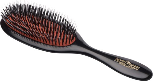 A black hairbrush with orange and black bristles, made of plastic, lies horizontally.