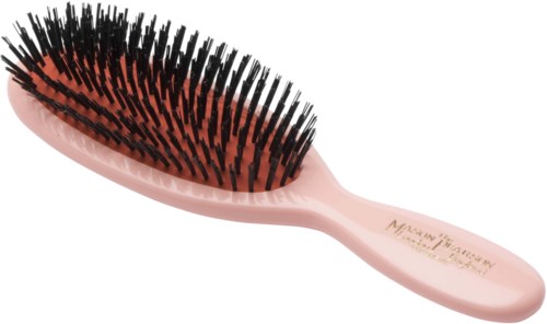 A pink hairbrush with black bristles and a curved shape. The handle has some text printed on it.