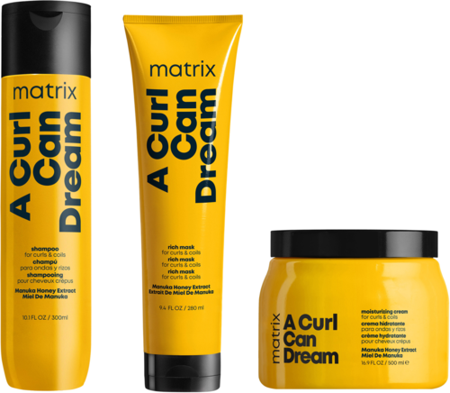 Gelbe Haarpflegeflaschen und Glas mit schwarzen Deckeln, beschriftet 'A Curl Can Dream' und 'matrix', vor weißem Hintergrund.