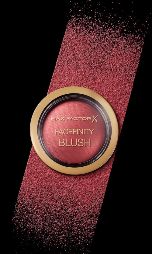 Ein runder Blush-Container mit goldener Kante, rosa Puder wird auf schwarzem Hintergrund verteilt. Beschriftung liest "Facefinity Blush."
