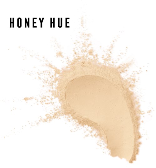 Valkoinen hivelly beige jauhepöly, kaareva muoto ja teksti "HONEY HUE" päällä.